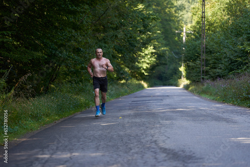 Athletic shirtless man running on road