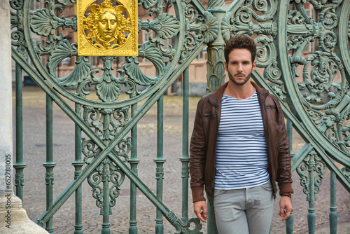A man standing in front of a green gate in Piazza Castello in Turin, Italy
