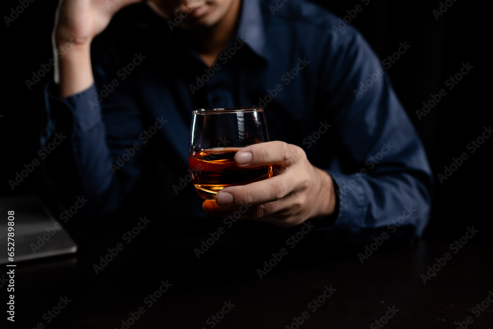 A man drinks whiskey, a businessman relieves stress from work sitting and drinking whiskey in the office after finishing a hard job, a drunk man. Alcohol drinking concept. A man drinks whiskey, a businessman relieves stress from work sitting and drinking whiskey in the office after finishing a hard job, a drunk man. Alcohol drinking concept.
