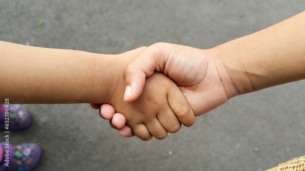 Close up view of kids handshake. Two children's hands holding each other. Close up view of kids handshake. Two children's hands holding each other.