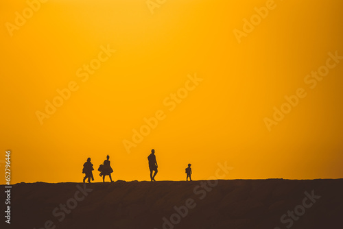 Silhouettes of people walking on a hill at a bright sunset