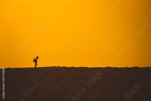 A little boy standing on the hill at sunset