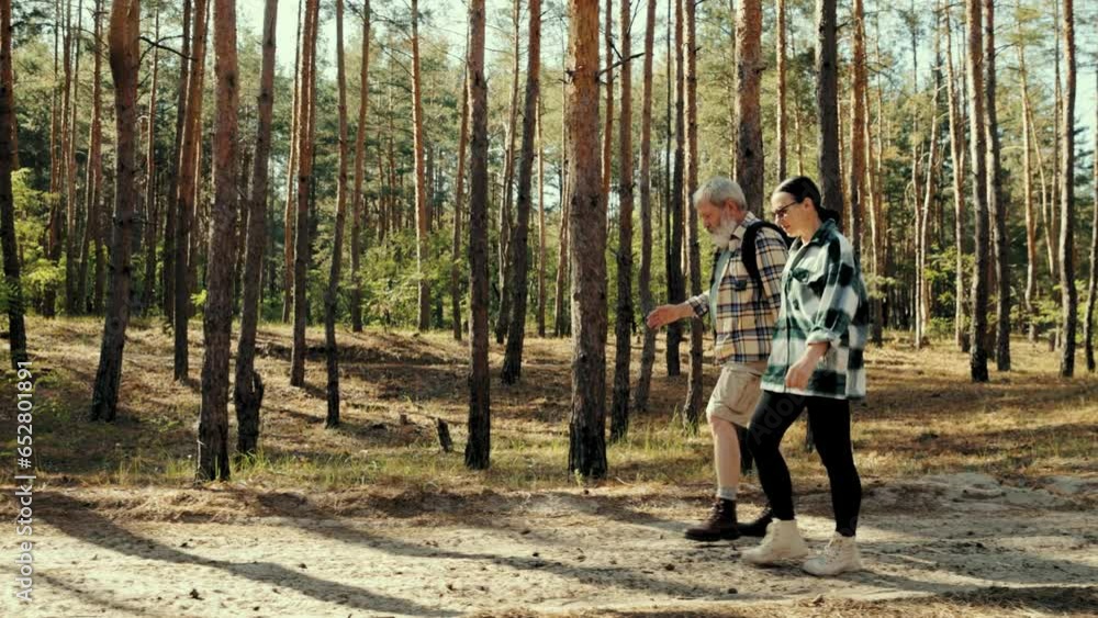 Stylish senior people, man and woman walking in forest on warm sunny day, talking, spending good active time together. Concept of leisure time, active lifestyle, hobby, weekends, nature Stylish senior people, man and woman walking in forest on warm sunny day, talking, spending good active time together. Concept of leisure time, active lifestyle, hobby, weekends, nature