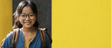 Cheerful schoolgirl happy to go to school on a yellow background, education