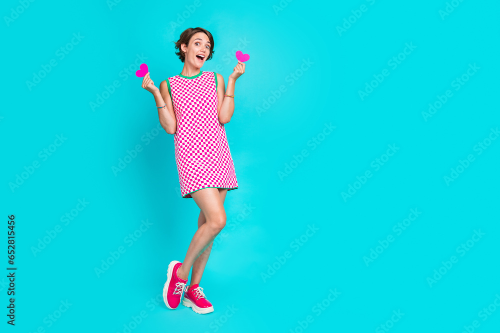 Full body photo of excited laughing young woman hold two postcards unexpected happy valentine day sale isolated on cyan color background Full body photo of excited laughing young woman hold two postcards unexpected happy valentine day sale isolated on cyan color background