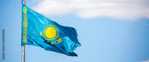 Fotografie The flag of Kazakhstan is fluttering in the wind against the blue sky