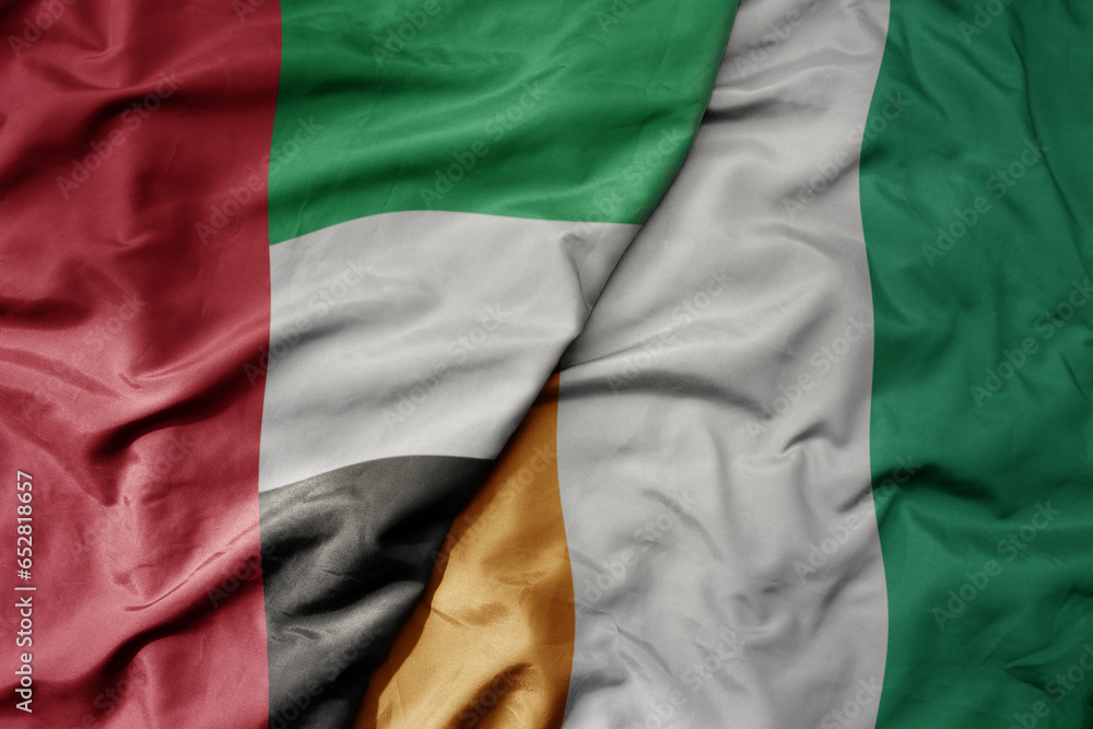 big waving realistic national colorful flag of united arab emirates and national flag of cote divoire .