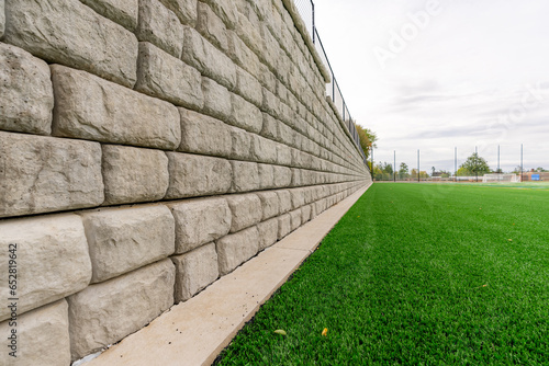 Retaining wall next to a green synthetic turf athletic field. photo