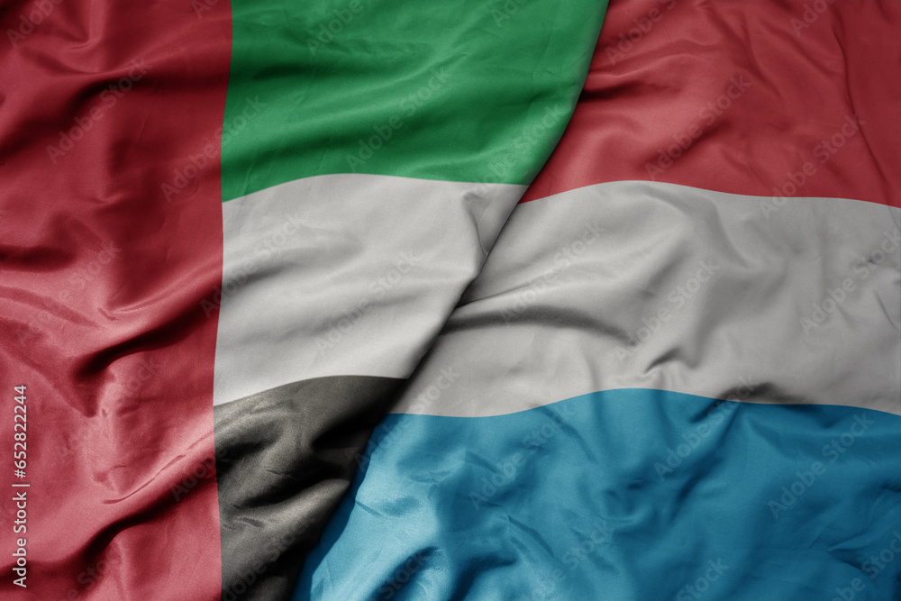 big waving realistic national colorful flag of united arab emirates and national flag of luxembourg .