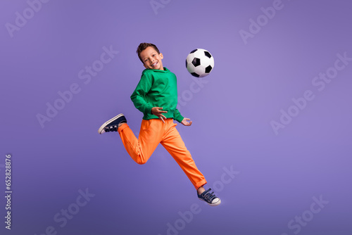 Photo of positive optimistic boy team member running training football isolated on purple color background