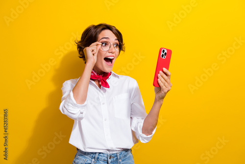 Photo of young girl wear white shirt red kerchief neck touch eyeglasses shocked tweet crazy elon musk isolated on yellow color background photo