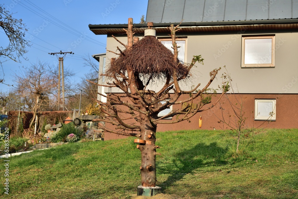 Large bird feeder with a roof made of branches and nesting box
