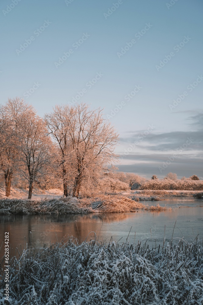 Idyllic winter scene of a tranquil river covered in a layer of ice, illuminated by the setting sun