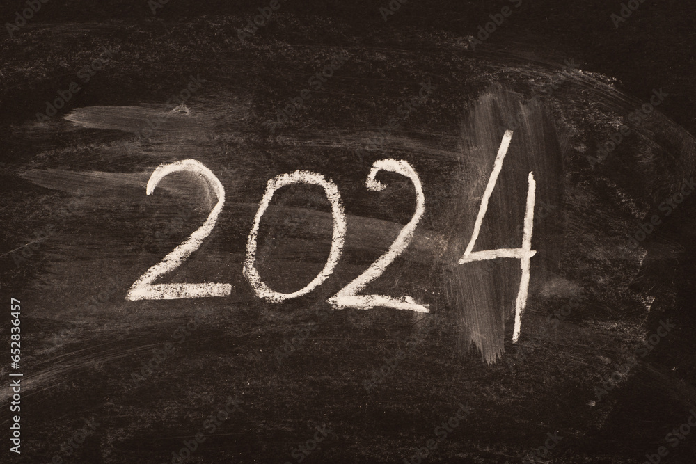 The number 2024 is written in chalk on a blackboard as a symbol of the coming New Year. - obrazy, fototapety, plakaty 