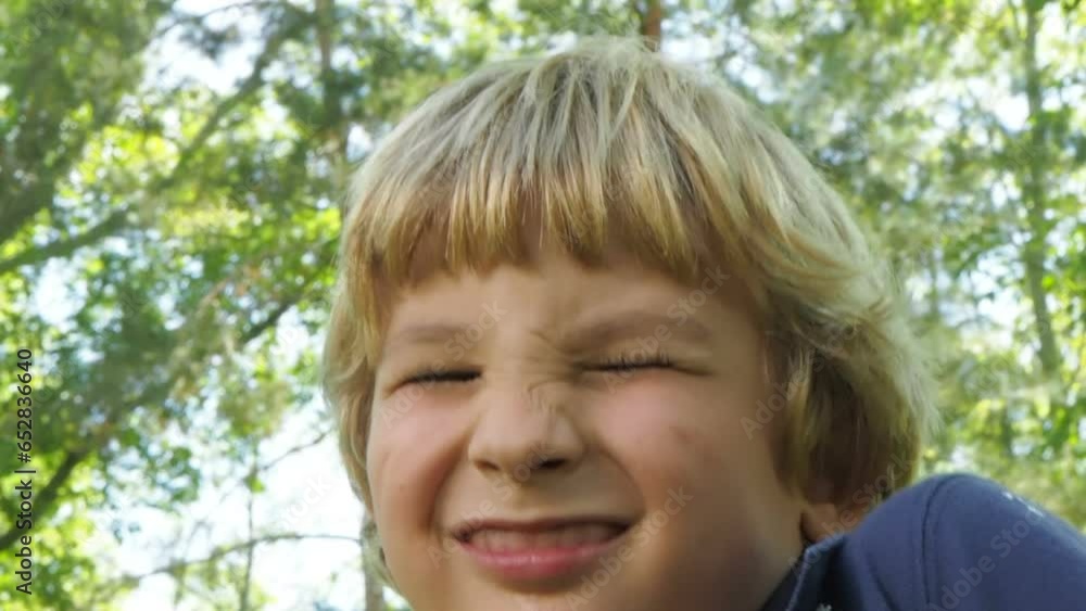 Portrait of a happy blonde Caucasian kid under sunny trees in the forest Portrait of a happy blonde Caucasian kid under sunny trees in the forest