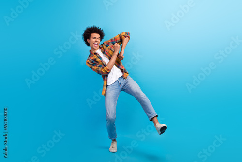 Full length photo of cheerful positive guy dressed checkered shirt dancing having fun isolated blue color background © deagreez