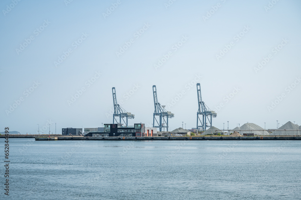 Three blue freight cranes at Aarhus Harbor Port, view from the distance, clear sky, denmark