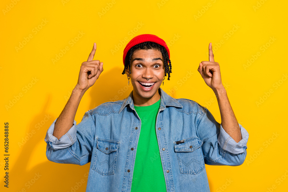 Photo of excited cheerful guy wear trendy jeans jacket two arms demonstrate low price offer empty space isolated on yellow color background