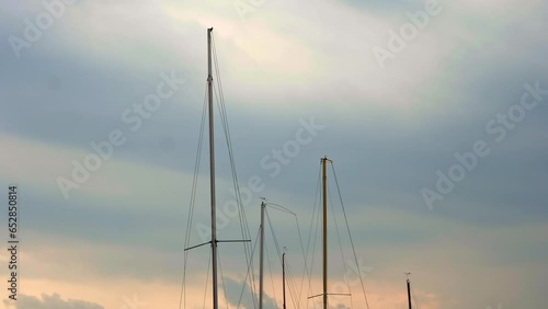 Yachting. seascape. sunset sky. masts of sailing yachts swinging in the wind, against the sky, at sunset. cloudy weather. Cinematic frame.  photo