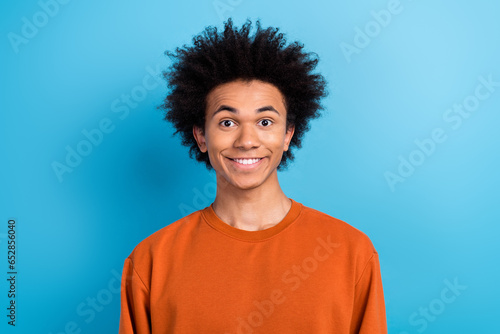 Portrait of candid sincere optimistic guy with afro hairstyle dressed brown pullover toothy smiling isolated on blue color background