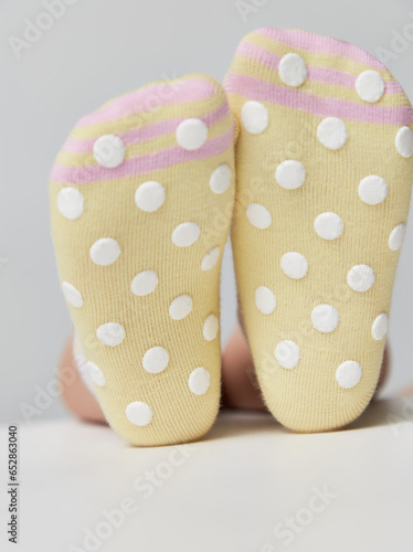  baby anti-slip socks on a white background. Children wearing pair of socks. Top view to kids foots in mismatched socks sitting on grey background. Beautiful baby feet in cute socks. 