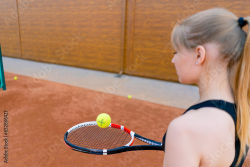 young girl beginner tennis player hitting the ball with a racket on the court practicing and learning to hit and serve sport hobby close-up © Guys Who Shoot