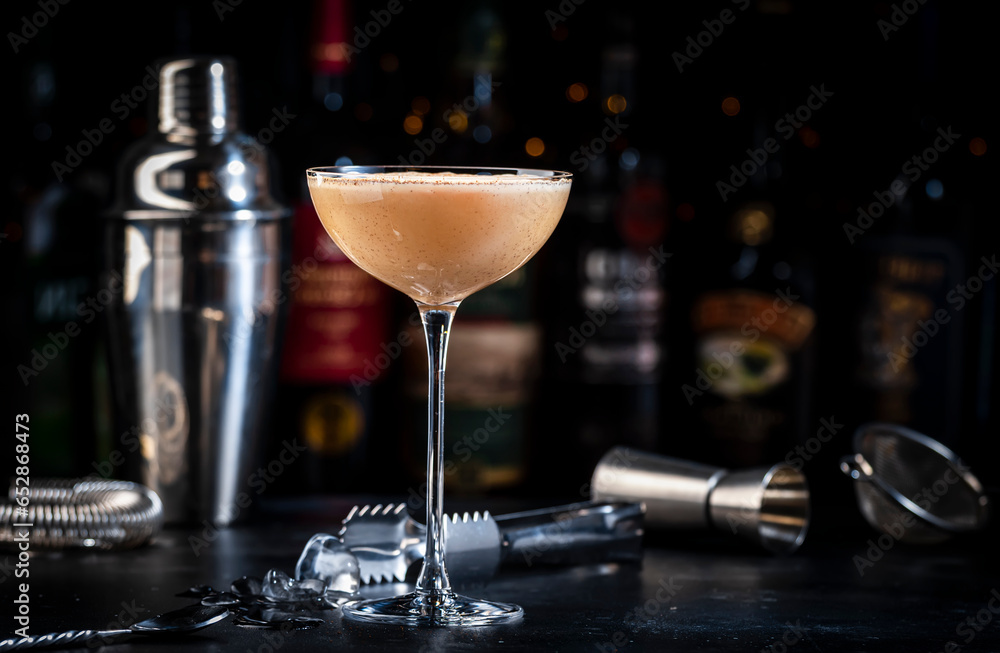 Rattlesnake coffee cocktail drink with cocoa liquor, irish cream, ground coffee and ice in glass, dark bar counter background, bar tools and bottles Rattlesnake coffee cocktail drink with cocoa liquor, irish cream, ground coffee and ice in glass, dark bar counter background, bar tools and bottles