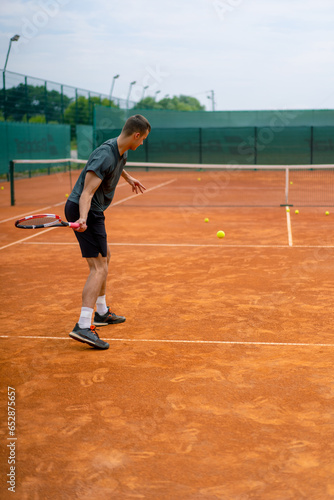 young professional player coach on outdoor tennis court practices strokes with racket and tennis ball