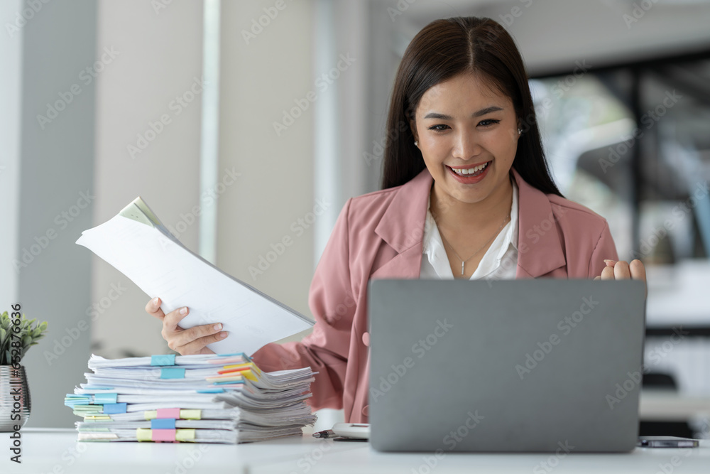 Cheerful and happy businesswoman working on laptop and financial documents in office, attractive smiling female office worker successful. Cheerful and happy businesswoman working on laptop and financial documents in office, attractive smiling female office worker successful.