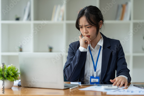 Young Asian businesswoman tired from working long hours, stressed, tired of thinking. Ideas for planning, presenting financial reports, investments, business plans, modern concepts online.