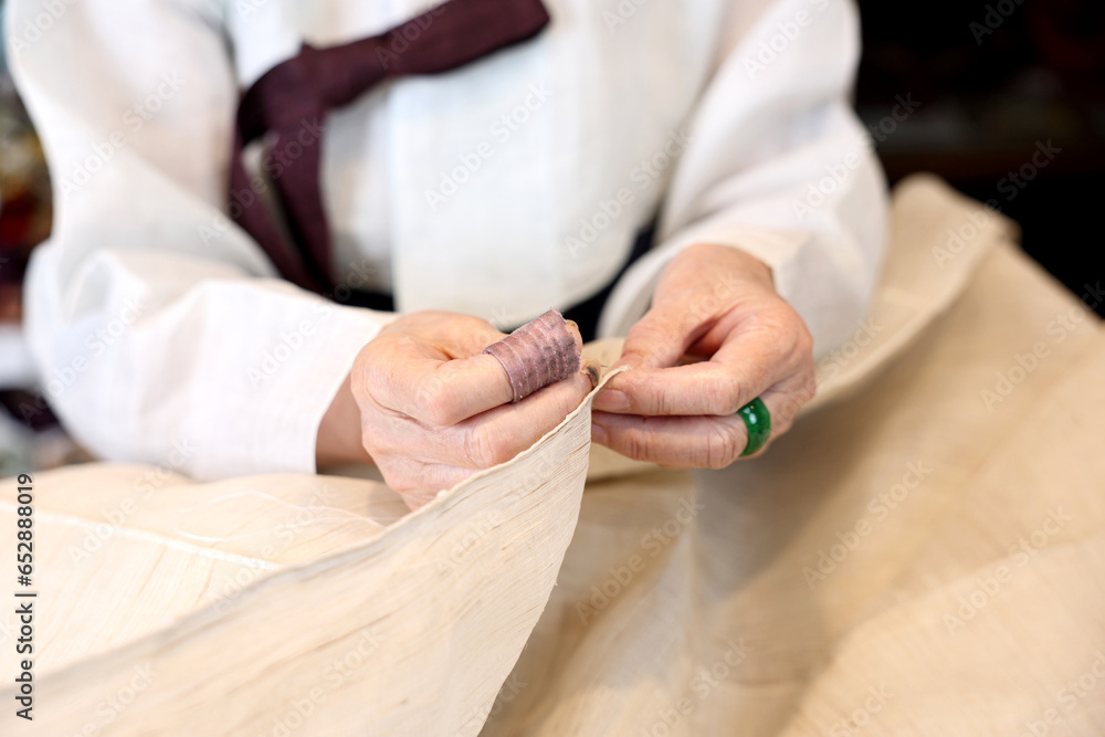 Obraz premium 한국 전통복장인 한복 명인이 한복 제작을 위해 바느질을 하고있다