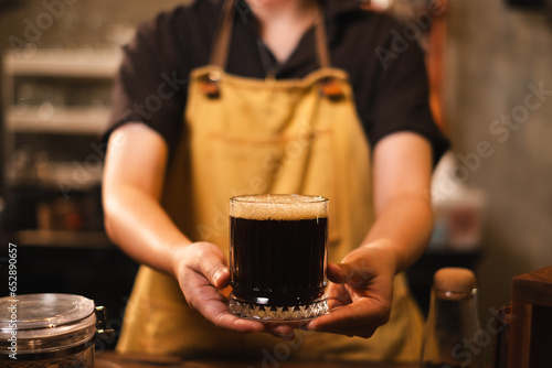 SME or start up business owner is serving Black coffee or americano in loft aroma coffee shop or cafe counter bar. Concept of slow bar, coffee caffeine. Black and brown style. Preparation of coffee.