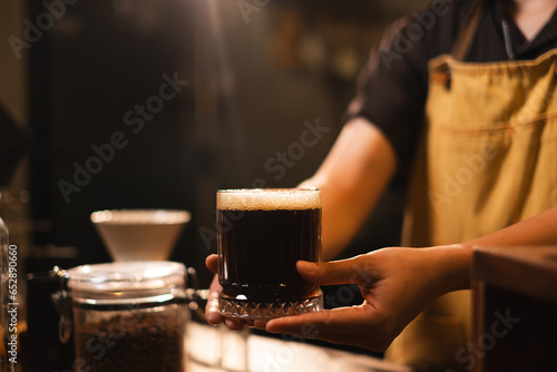 SME or start up business owner is serving Black coffee or americano in loft aroma coffee shop or cafe counter bar. Concept of slow bar  coffee caffeine. Black and brown style. Preparation of coffee.