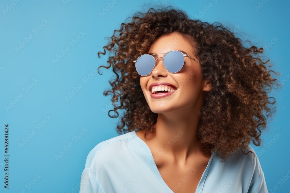 smiling cheerful african american curly stylish casual female woman wear sunglasses studio shot on blue color wall backdrop portrait shot smiling cheerful african american curly stylish casual female woman wear sunglasses studio shot on blue color wall backdrop portrait shot