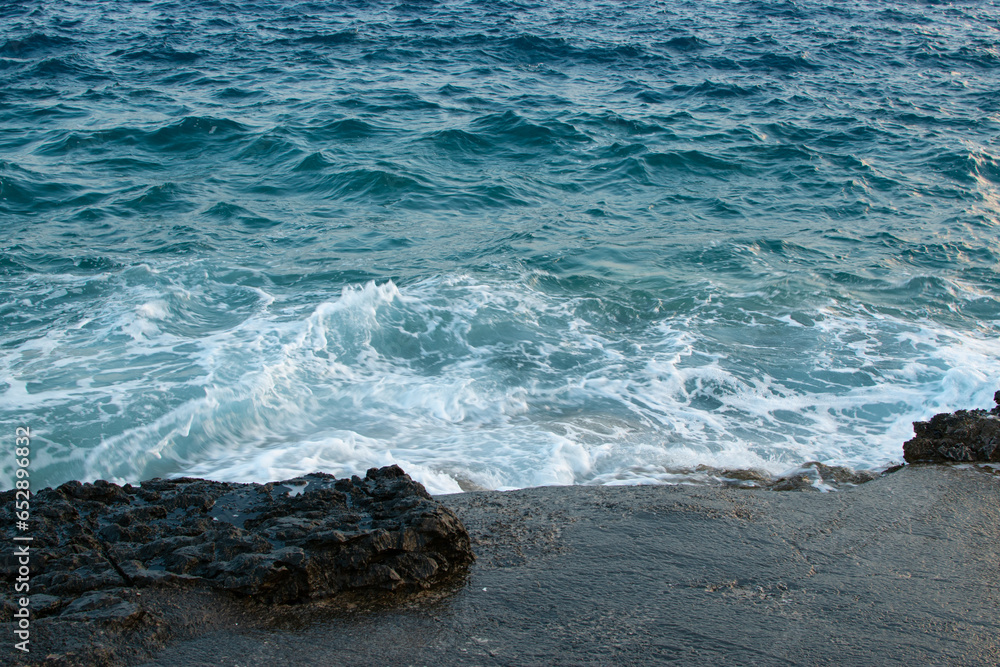 Fototapeta premium Sea waves break on a rocky beach, a coastline nature concept.