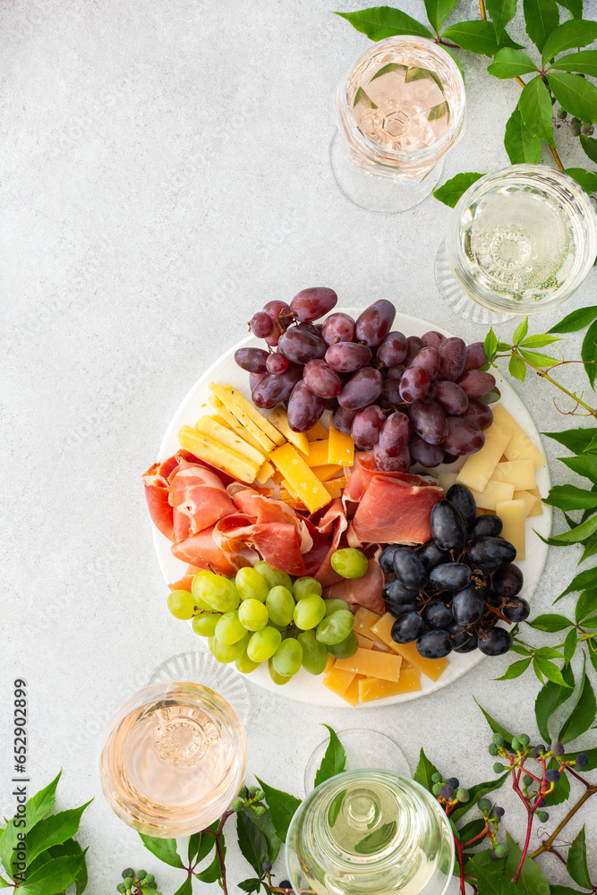 Outdoor wine tasting, picnic and relaxing with friends, glasses of wine and cheese board with grapes and jamon, top view Outdoor wine tasting, picnic and relaxing with friends, glasses of wine and cheese board with grapes and jamon, top view
