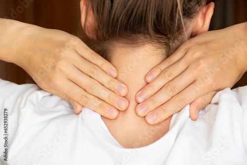 A girl holds her hands behind her neck , sore neck, acute pain in the neck