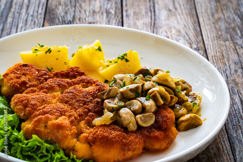 Fotografie Crispy breaded seared chicken cutlet with fried white mushrooms and boiled potat