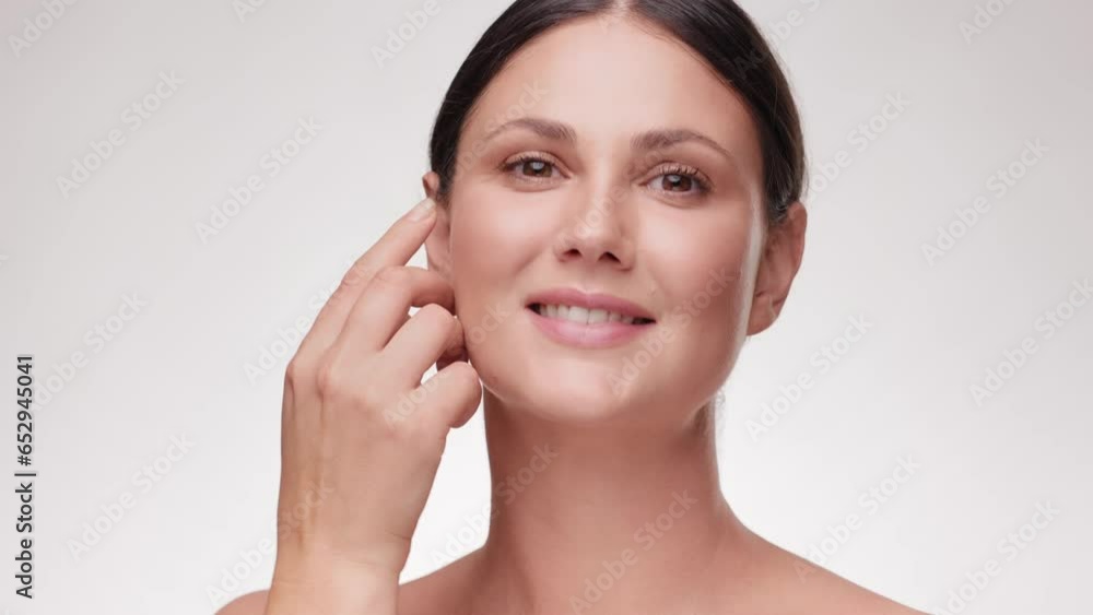 Close up Portrait beautiful Caucasian face. Woman touching her face skin. Happy Female with fresh glowing hydrated facial skin and natural makeup on light background at studio. Skin care concept. Close up Portrait beautiful Caucasian face. Woman touching her face skin. Happy Female with fresh glowing hydrated facial skin and natural makeup on light background at studio. Skin care concept.