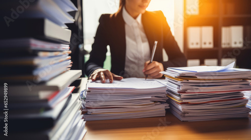 Businesswoman hands working in stacks of paper searching for information