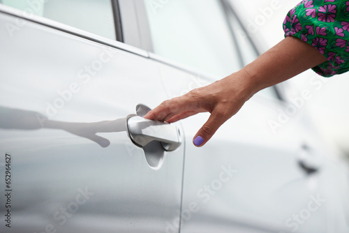 An adult woman opens the car door.