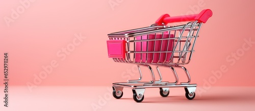 Online shopping with delivery service allows consumers to shop from home using a red shopping cart or paper boxes on a pink background with copy space available