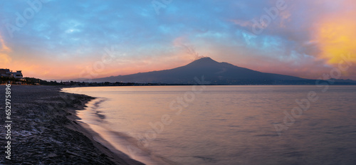 Beautiful sunset twilight on Agnone Bagni sea beach with smoky Etna volcano in far (Siracusa, Sicily, Italy). 