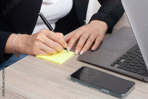 Close up of woman hand working on laptop computer and writing on notebook with a pen, online working from home. Student studying online class, E-learning, digital education concept