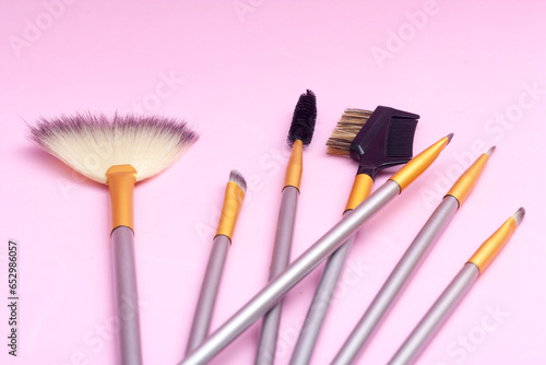 Pink background with an assortment of make up brushes with space for copy. Overhead shot