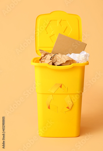 Container for garbage with paper on beige background. Recycling concept