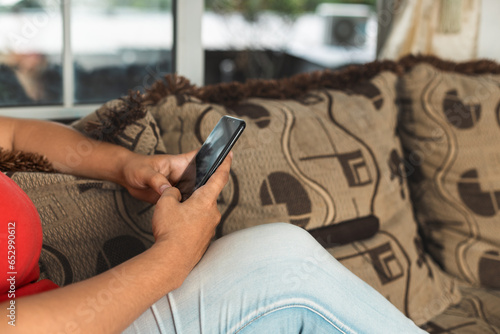 unrecognizable person sitting in an armchair, typing on the cell phone, hopefully red, photo