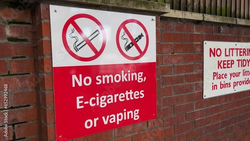 Large wall-mounted public information sign at a UK transport terminus. The sign carries the text ‘No Smoking, E Cigarettes, or Vaping’.