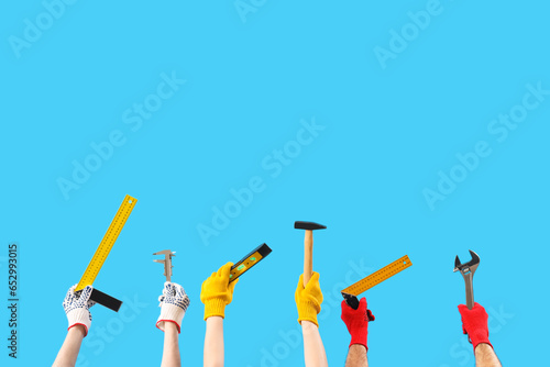 Female and male hands holding different construction tool on blue background