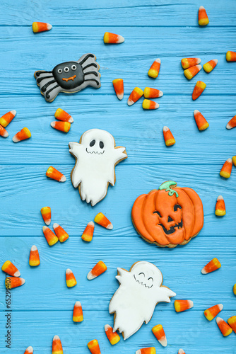 Tasty Halloween candy corns and cookies on color wooden background